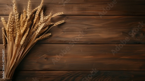 A rustic image of a wheat sheaf lying on a dark wooden background