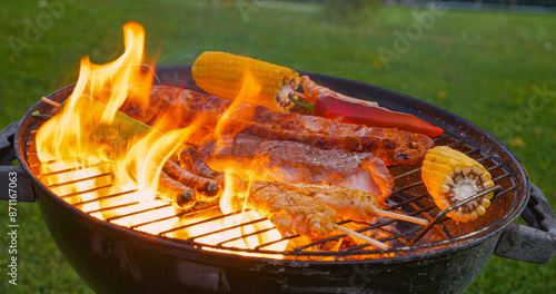 CLOSE UP: Roasted meat and vegetables and flared up fire flames on the grill