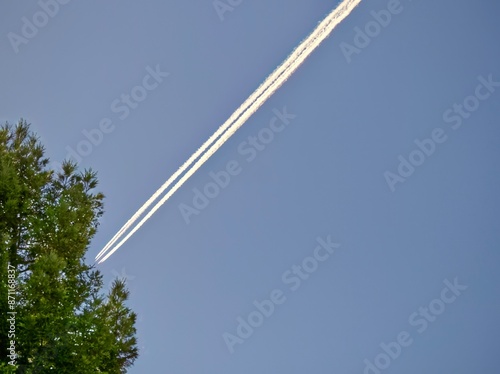 Long whits contrails cut diagonally through a clear blue sky