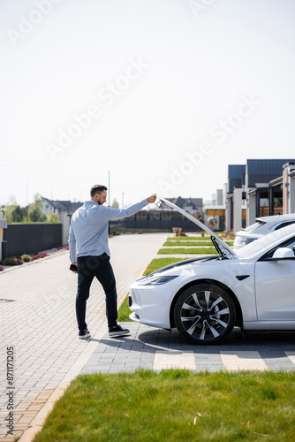 A man closes the trunk of a car photo