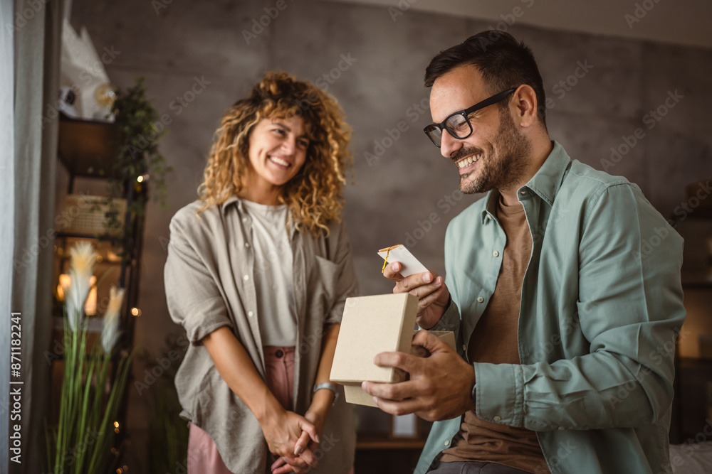 Surprised boyfriend hold gift read greeting card from his girlfriend Surprised boyfriend hold gift read greeting card from his girlfriend
