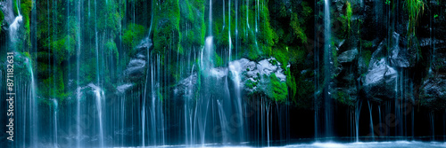 Lush waterfall with green foliage and granite rocks photo
