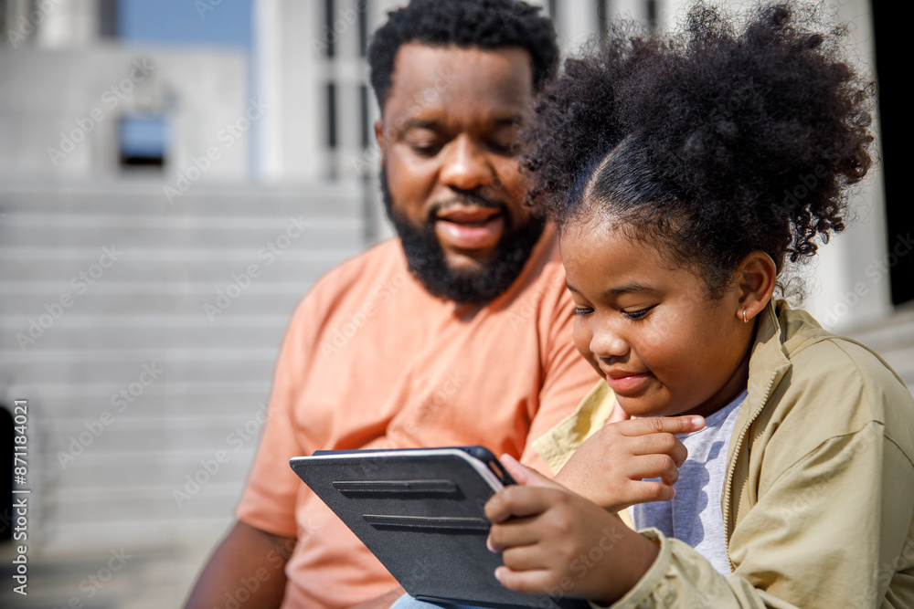 Girl using tablet PC by father on sunny day Girl using tablet PC by father on sunny day