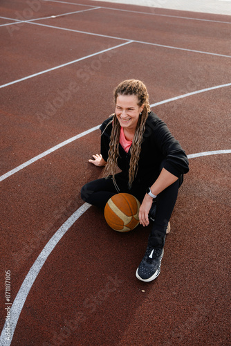 A woman is sitting on a basketball field