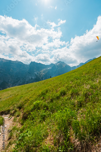 Paraglider with Backpack Walking Up the Hillside in the Mountain Landscape