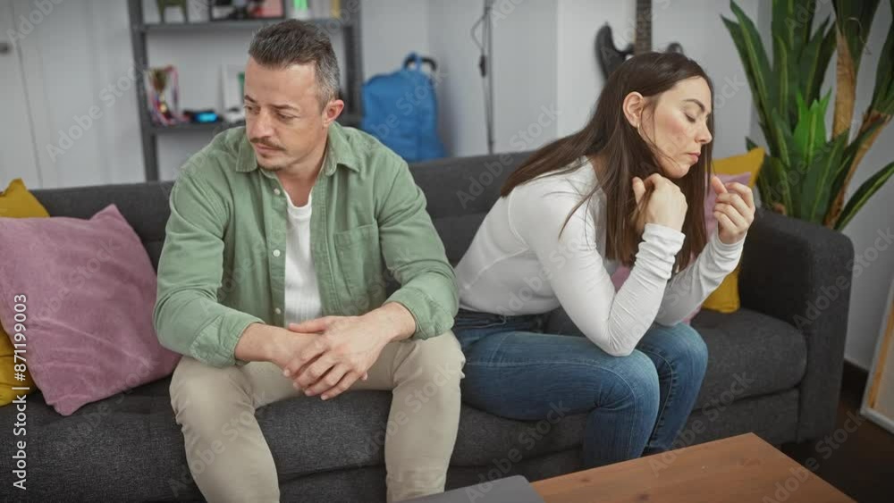 A couple experiencing tension, with the upset woman and concerned man sitting indoors. A couple experiencing tension, with the upset woman and concerned man sitting indoors.
