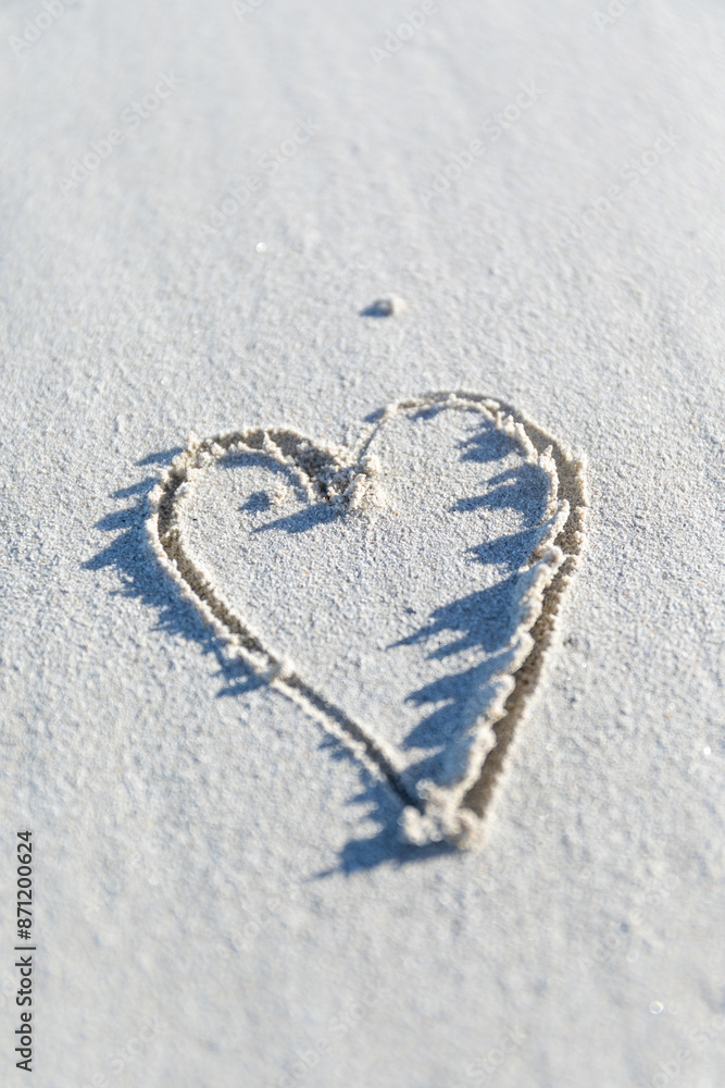 Small love heart drawn on a beach. Sandy beach with copy space.