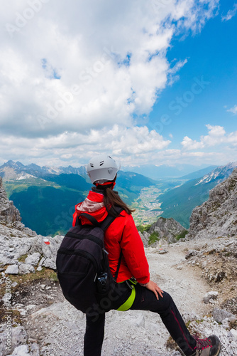 Woman Hiker with Helmet Looking Down the Rocky Mountain Summit photo