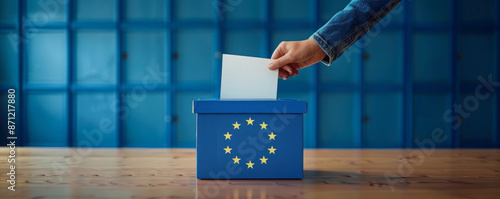 Voting for the European Union election, a hand putting a ballot paper into a ballot box on a blue background with copy space photo