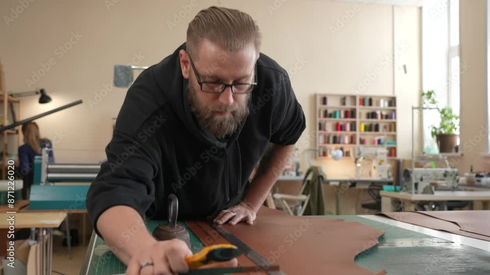 Leatherworker measuring and cutting leather in workshop. Leatherworker measuring and cutting leather in workshop.