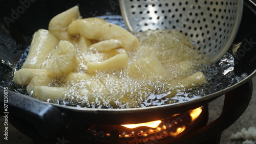 Cassava is being fried on a frying pan. Fried cassava is a traditional Indonesian food. Focus selected