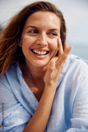 Happy woman applies cream to her face