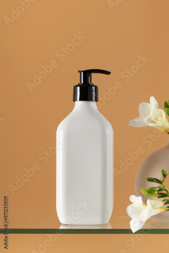 Blank plastic cosmetic product dispenser bottle and freesias © Виктория Попова