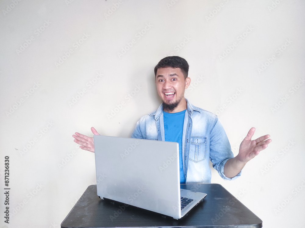 Asian mature man smiling confidently looking at the camera while working in front of his laptop Asian mature man smiling confidently looking at the camera while working in front of his laptop
