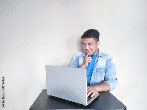 A man on his working place looking to laptop with shocked expression photo