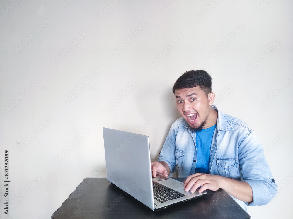 Asian mature man smiling confidently looking at the camera while working in front of his laptop Asian mature man smiling confidently looking at the camera while working in front of his laptop