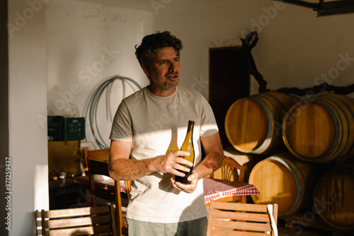 Proprietor of a small winery holds a bottle of artisanal wine photo