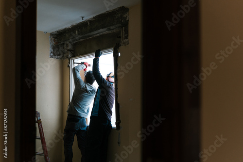 Focused handymen workers installing window in apartment photo