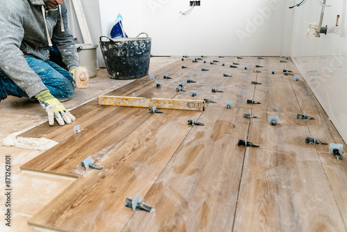 Anonymous tile layer installing modern wood flooring during renovation photo