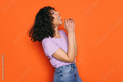 Moroccan woman laughing joyfully against a vivid orange background