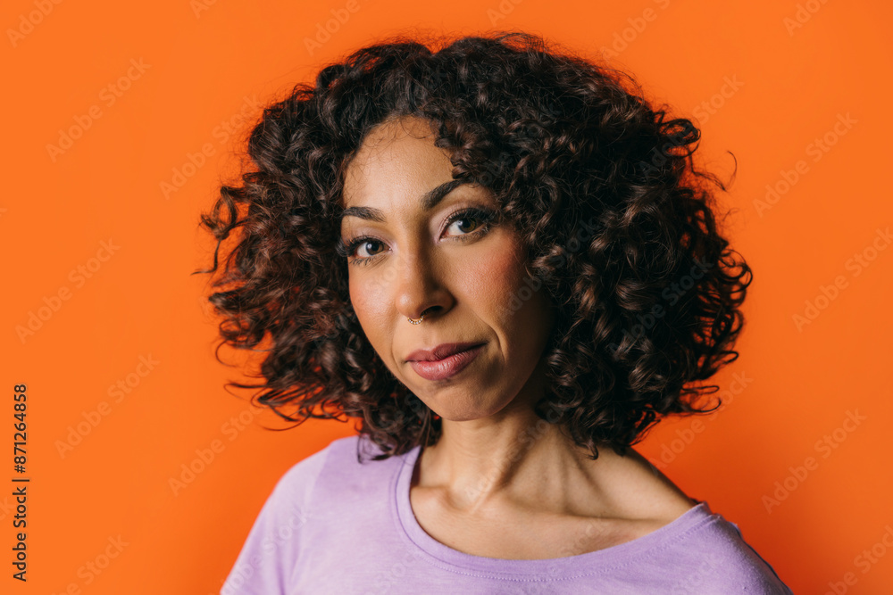 Moroccan woman with curly hair against bright orange background Moroccan woman with curly hair against bright orange background