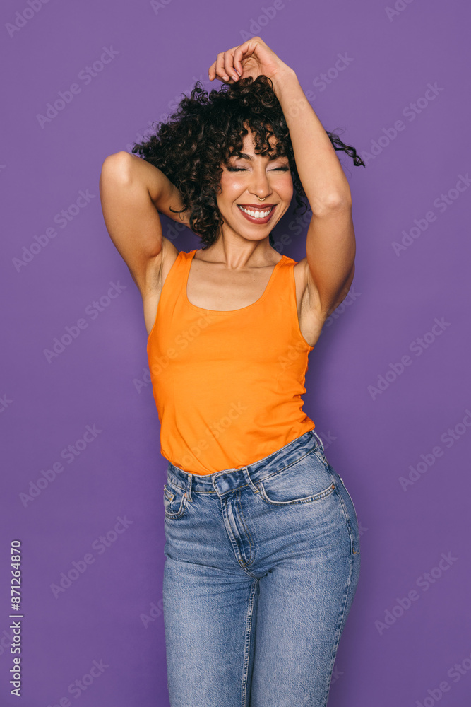 Happy woman in orange tank top and jeans posing on purple background Happy woman in orange tank top and jeans posing on purple background