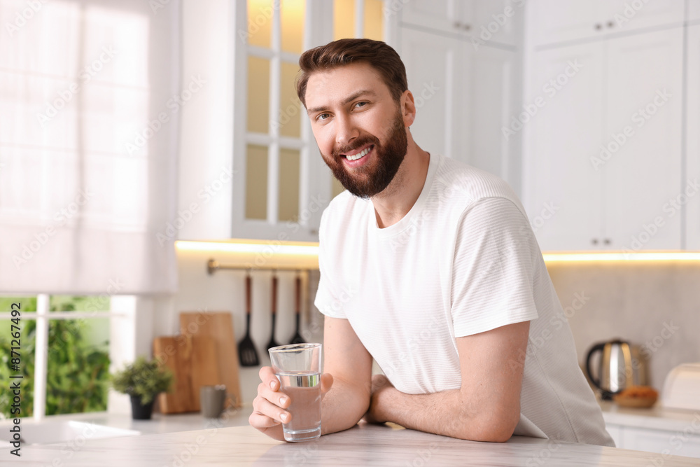 Happy young man with glass of water in kitchen at morning Happy young man with glass of water in kitchen at morning
