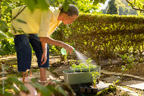 Photography Watering plants in garden, mature woman nurturing her home garden