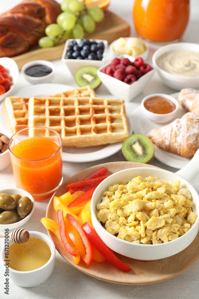 Tasty breakfast. Scrambled eggs in bowl, bell pepper, honey and other food on light table, closeup Tasty breakfast. Scrambled eggs in bowl, bell pepper, honey and other food on light table, closeup