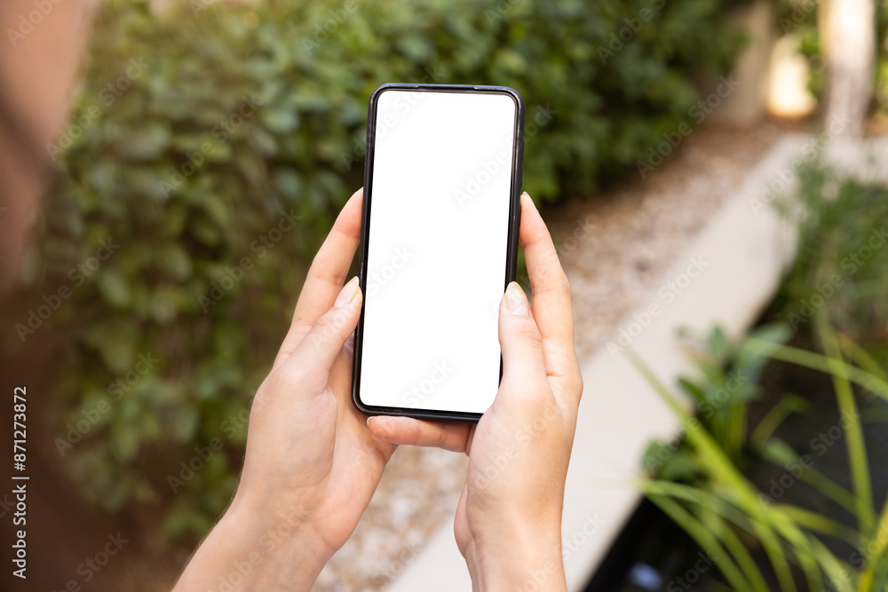 Holding smartphone with blank screen, person outdoors in garden setting, copy space Holding smartphone with blank screen, person outdoors in garden setting, copy space