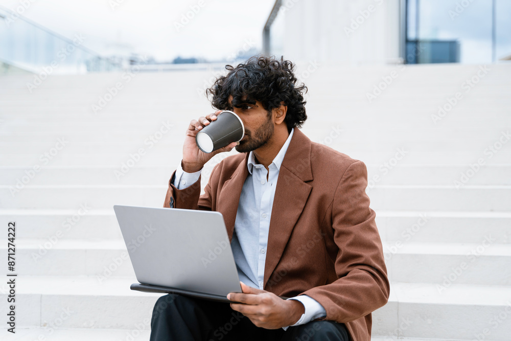 A man uses a laptop sitting on the stairs A man uses a laptop sitting on the stairs