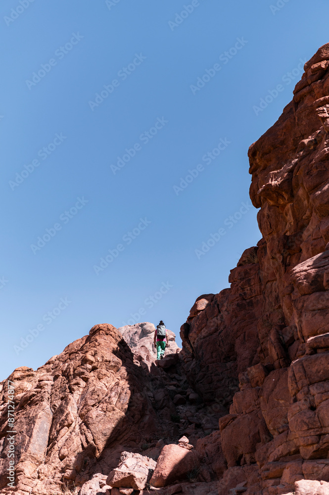 Hiker hiking rocky trail in desert mountain in summer Hiker hiking rocky trail in desert mountain in summer