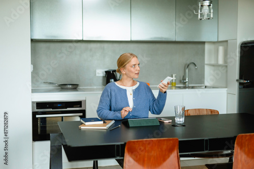 A woman controls the air conditioner using a remote control photo