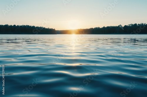 A serene sunset over a tranquil lake, with the sun casting a golden glow on the water.  The image evokes feelings of peace and tranquility. photo