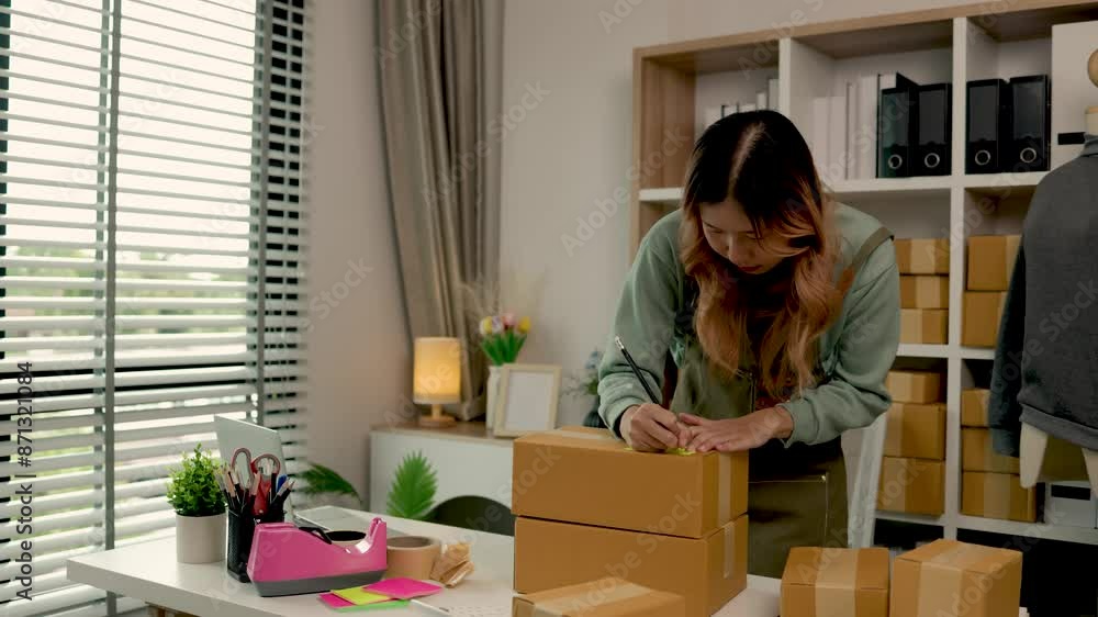 she is packing clothes into the box, preparation of product that she sell to waiting for delivery man to sent to customer, an Asian woman works in clothing store packing product into parcel she is packing clothes into the box, preparation of product that she sell to waiting for delivery man to sent to customer, an Asian woman works in clothing store packing product into parcel
