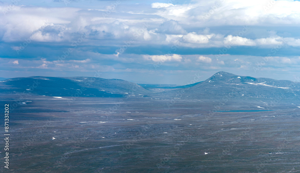 Wild barren mountain tops in a vast empty polar landscape of northern Norway. In the distance a pointy peak, as a view from Bolnatind, Helgeland, Norway. Fjell of the arctic circle. Cold blue mountain Wild barren mountain tops in a vast empty polar landscape of northern Norway. In the distance a pointy peak, as a view from Bolnatind, Helgeland, Norway. Fjell of the arctic circle. Cold blue mountain