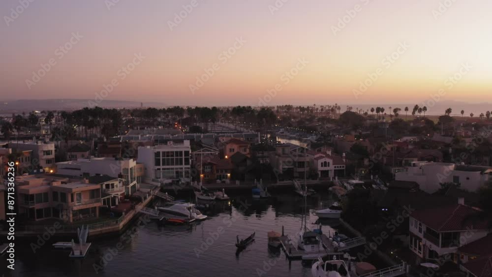 Aerial view of sunset over Coronado in San Diego California overlooking residential areas and the Pacific Ocean and bay with boats docked near luxury homes with colorful sky
