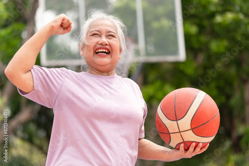 Active senior woman playing basketball in the urban outdoor basketball court, healthy life concepts