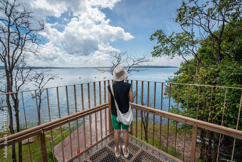 The young girl on the steel mesh skywalk and looking at the dam view in Sirindhorn Dam at Ubon Ratchathani, Thailand photo