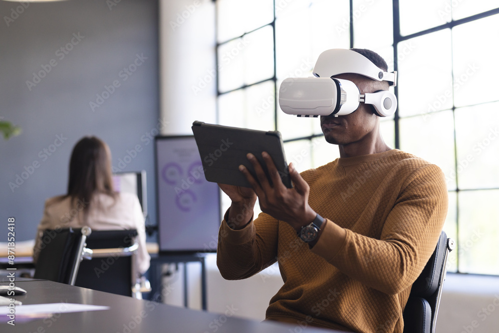 Using VR headset and holding tablet, man working in modern office setting Using VR headset and holding tablet, man working in modern office setting