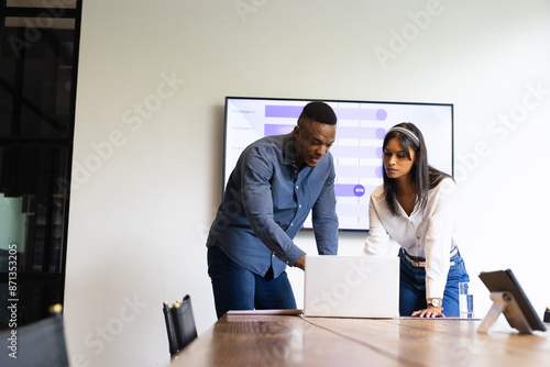 Collaborating on project, colleagues discussing data using laptop in office meeting photo