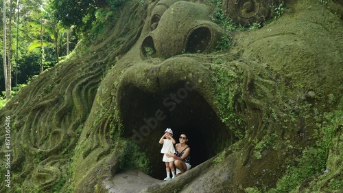 Female Tourist And Daughter Posing At Mouth Cave In Alas Harum Bali, Tegallalang, Indonesia. panning, slow motion photo