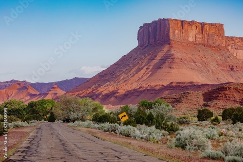 Desert road, butte and mesa rock formations in the desert at sunrise. Moab, Utah, United States of America.