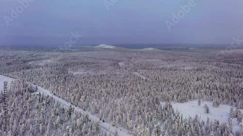 Aerial view over snowy woodlands, toward fells of Lapland, gloomy winter morning photo