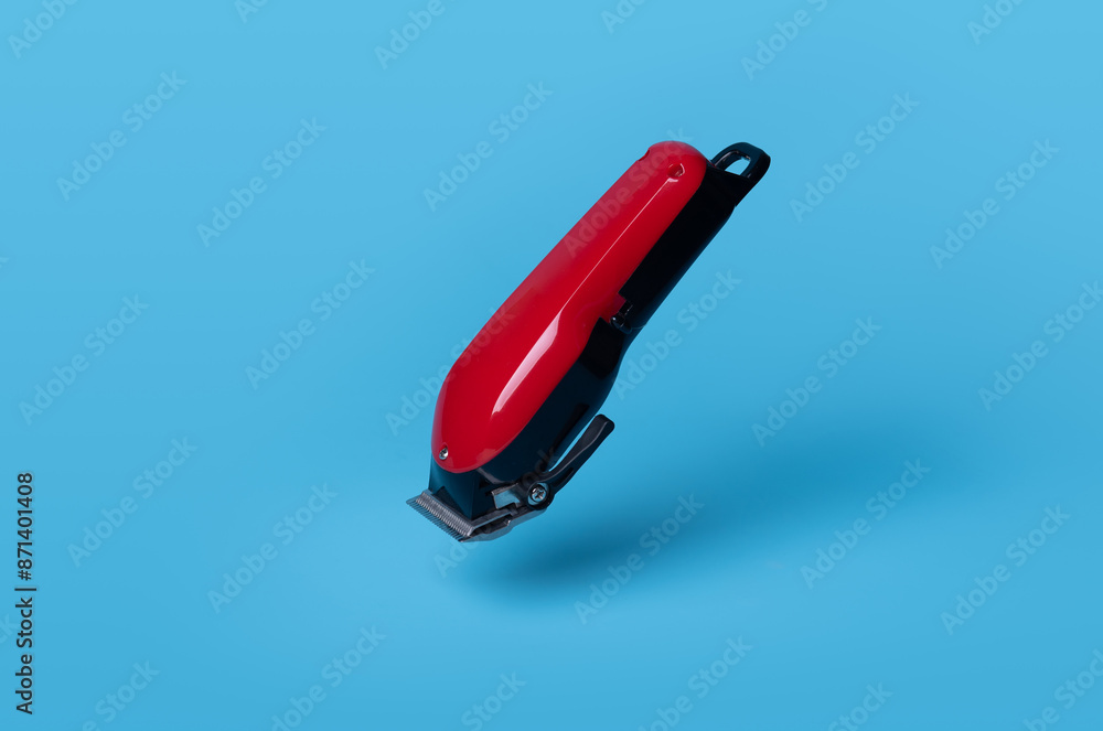 Black and red battery operated hair clippers on blue background Black and red battery operated hair clippers on blue background