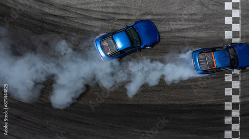 Aerial top view two cars drifting battle on asphalt race track with lots of smoke from burning tires, Two race cars competition drift battle view from above. photo