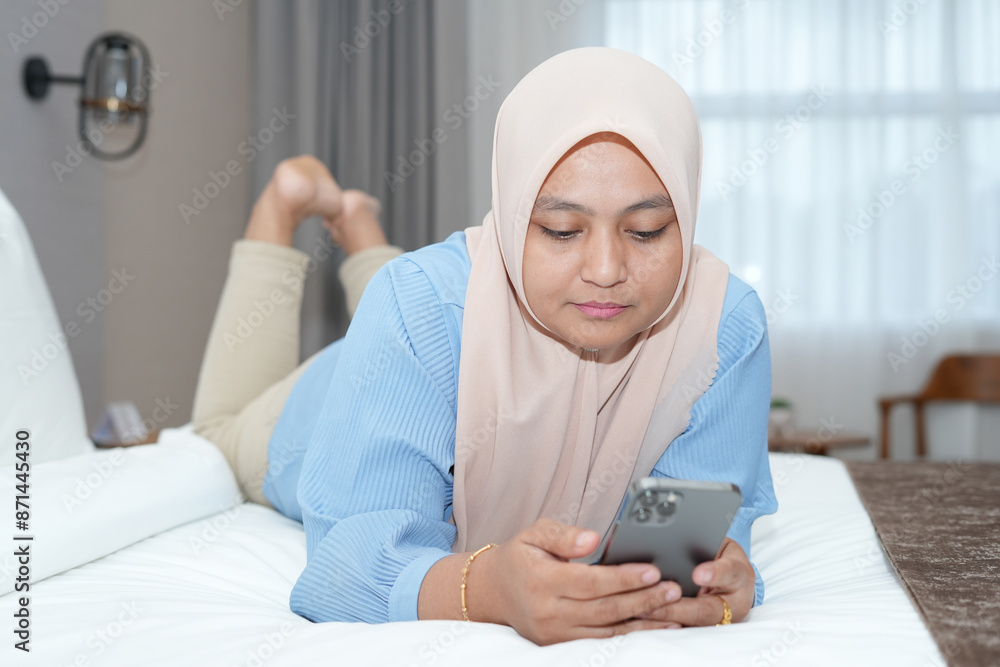 Muslim woman is using a cell phone in bed Muslim woman is using a cell phone in bed
