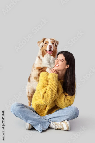 Young woman with Australian Shepherd dog sitting on light background photo