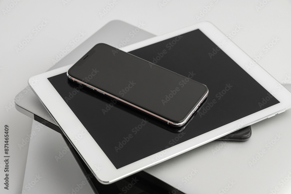 Stack of different modern gadgets on light background, closeup Stack of different modern gadgets on light background, closeup