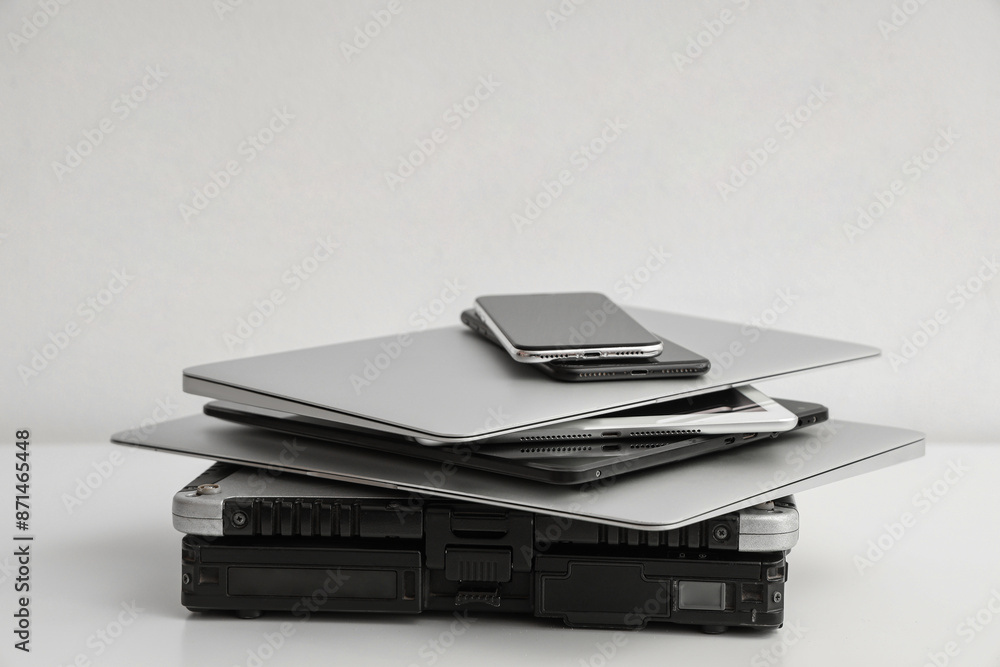 Stack of different modern gadgets on light background